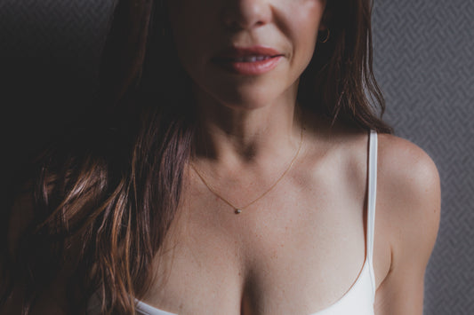 Woman wearing a white tank top with a neutral background