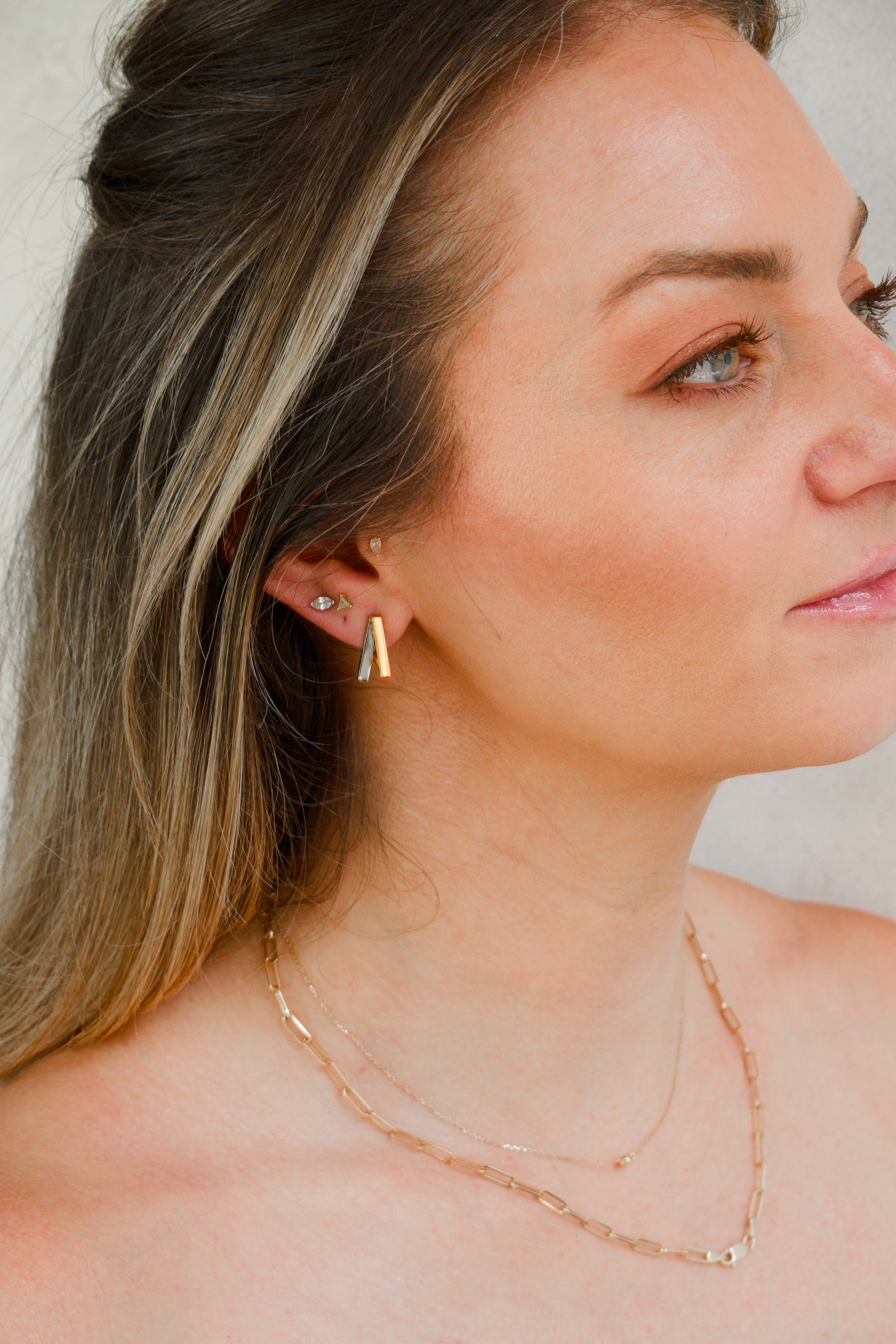 Woman wearing Armine + Ambrose The Namesake double A inverted huggie earring in mixed metal gold and silver