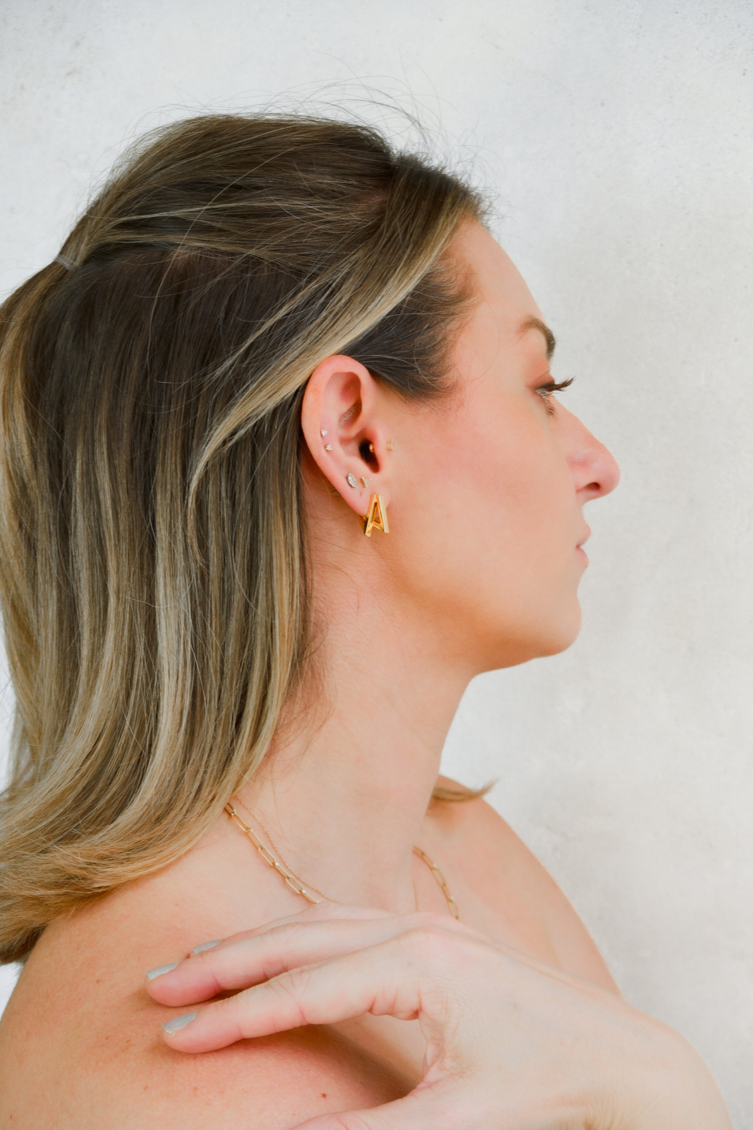 Woman wearing Armine + Ambrose The Namesake double A inverted huggie earrings on white background 