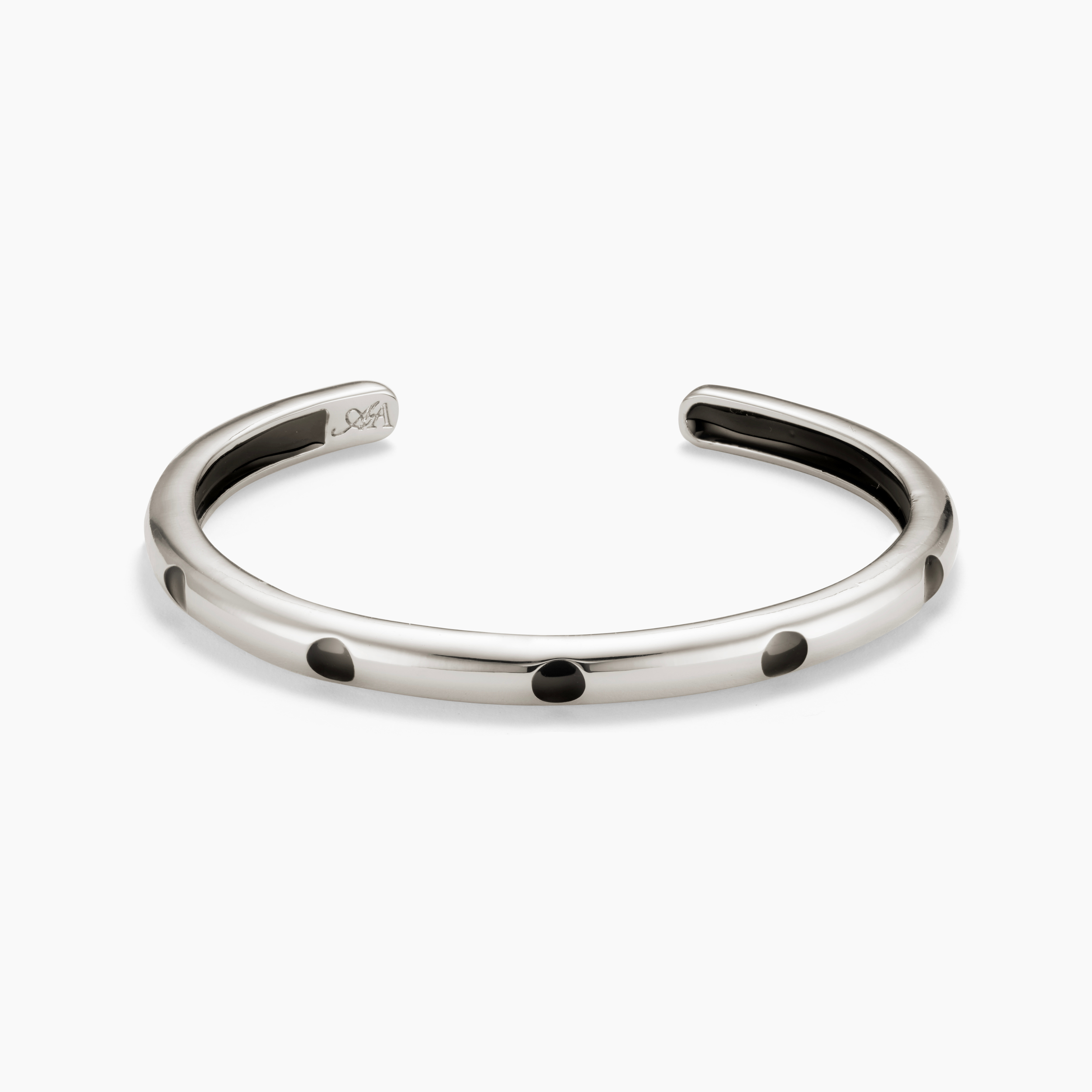 Silver bracelet with black dots on a white background