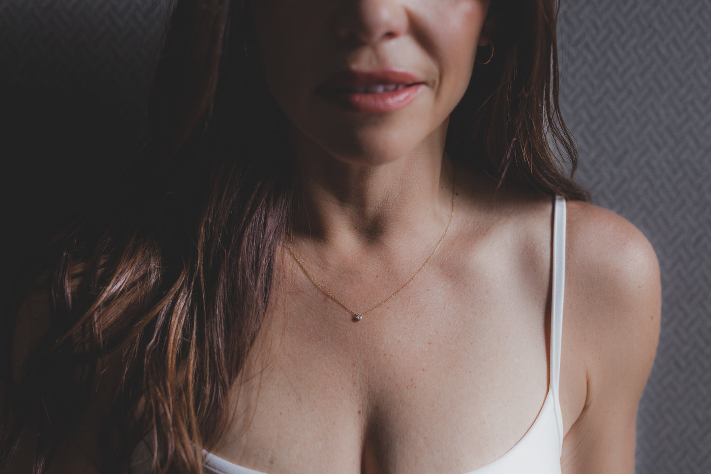 Woman wearing a white tank top with a neutral background