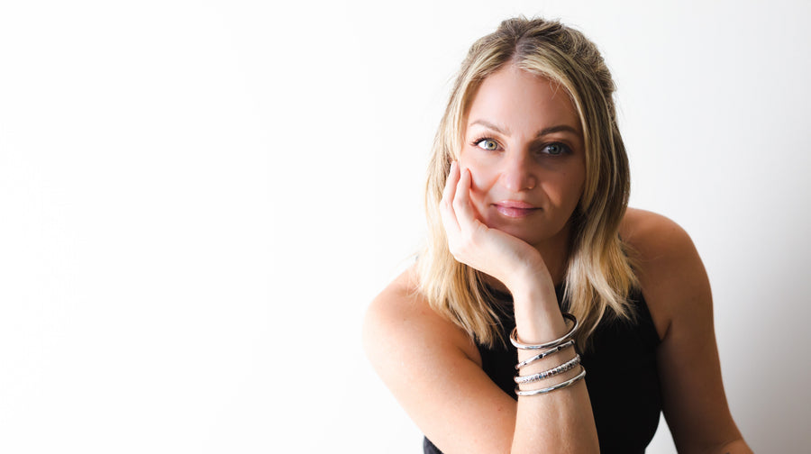 Woman with blonde hair and multiple bracelets on a white background