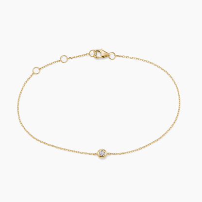 Gold bracelet with a small round diamond on a white background