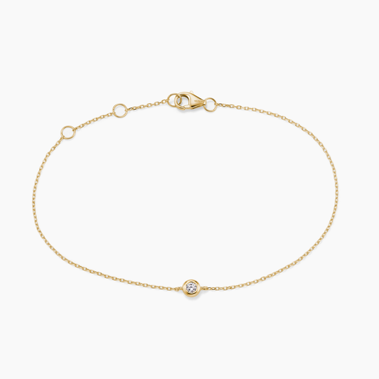 Gold bracelet with a small round diamond on a white background