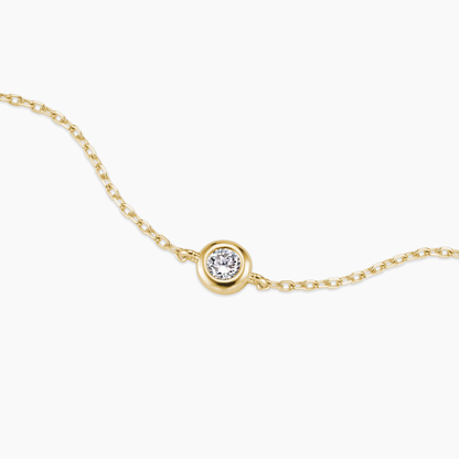 Gold necklace with a single diamond pendant on a white background