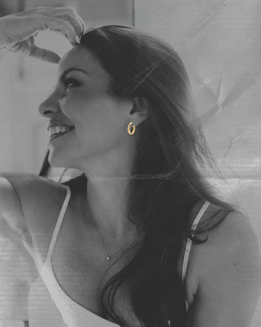 Woman wearing gold hoop earrings with a black and white background