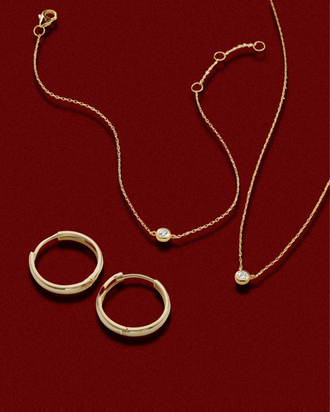 Gold necklace and hoop earrings on a red background