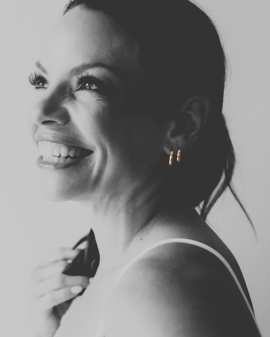 Black and white photo of a woman with a side profile, wearing gold earrings.